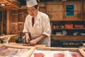 Sushi master chef preparing fresh tuna sashimi breakfast at the Tsukiji fish market in Tokyo