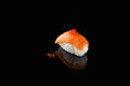 Sushi nigiri with salmon - Syake with red caviar on a black background with reflection. A dish of rice and red fish Royalty Free Stock Photo
