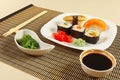 Sushi with omelet with eel and with salmon, rolls, hiyashi wakame salad and soy sauce on bamboo mat close up. Royalty Free Stock Photo