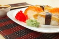 Sushi with omelet with eel and with salmon and soy sauce on black and red bamboo mat close up. Royalty Free Stock Photo