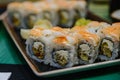 Sushi pieces are placed on a ceramic plate. sprinkled with flying fish caviar. bowls with wasabi, cinder, ginger and soy sauce