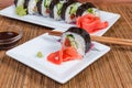 Sushi on plates, condiments, chopsticks on bamboo table mat closeup Royalty Free Stock Photo