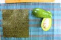 Sushi preparation in the kitchen, fresh ingredients green avocado cut in half with a seaweed and white cooked rice on a wooden cut Royalty Free Stock Photo