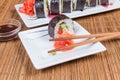 Sushi on rectangular plates, condiments, chopsticks on bamboo table mat Royalty Free Stock Photo