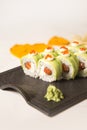 Sushi roll with avocado slices, red caviar on top on black plate, marble background Royalty Free Stock Photo