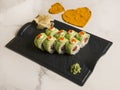 Sushi roll with avocado slices, red caviar on top on black plate, marble background Royalty Free Stock Photo
