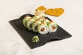 Sushi roll with avocado slices, red caviar on top on black plate, marble background Royalty Free Stock Photo