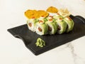 Sushi roll with avocado slices, red caviar on top on black plate, marble background Royalty Free Stock Photo