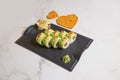 Sushi roll with avocado slices, red caviar on top on black plate, marble background Royalty Free Stock Photo