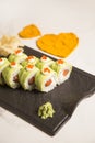 Sushi roll with avocado slices, red caviar on top on black plate, marble background Royalty Free Stock Photo