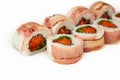 Sushi roll with bacon and salmon on a white background, ingredients seared bacon, salmon, green onions, flying fish roe, Iceberg Royalty Free Stock Photo