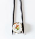 Sushi roll in black chopsticks isolated on white background. Japanese cuisine Royalty Free Stock Photo