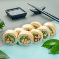 Sushi roll Caesar with smoked chicken, vegetables and cheese. Decorated with greenery. In the background is a gravy boat and