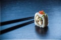 Sushi roll with caviar and chopsticks on black tableboard. Japanese food concept. Royalty Free Stock Photo