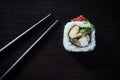 Sushi roll with caviar and chopsticks on black tableboard top view. Japanese food concept. Royalty Free Stock Photo