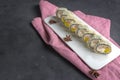 Sushi roll with chopsticks on a white plate. Pink napkin on a gray background and anise Royalty Free Stock Photo