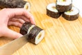 Sushi roll Japanese food maki cut by sharp knife on bamboo board