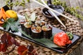 Sushi Roll - Maki Sushi with Smoked Eel, cucumber, avocado and sesame on black stone on bamboo mat decorated with flowers Royalty Free Stock Photo