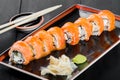 Sushi Roll - Maki Sushi made of salmon, cucumber, avocado and cream cheese on dark wooden background.