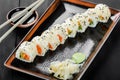 Sushi Roll - Maki Sushi made of salmon, orange, avocado and cream cheese on dark wooden background.