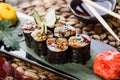 Sushi Roll - Maki Sushi with Smoked Eel, cucumber, avocado and sesame on black stone on bamboo mat decorated with flowers. Royalty Free Stock Photo