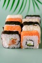 Sushi Roll Philadelphia with Salmon Cream Cheese on Fake Monstera Leaf on Green Background Sushi Menu Japanese Food Vertical