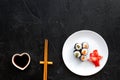 Sushi roll with salmon and avocado on plate with soy sauce, chopstick, wasabi on black background top view copyspace