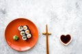 Sushi roll with salmon and avocado on plate with soy sauce, chopstick, wasabi on grey stone background top view Royalty Free Stock Photo