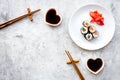 Sushi roll with salmon and avocado on plate with soy sauce, chopstick, wasabi on grey stone background top view Royalty Free Stock Photo