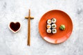Sushi roll with salmon and avocado on plate with soy sauce, chopstick, wasabi on grey stone background top view Royalty Free Stock Photo