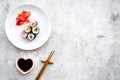 Sushi roll with salmon and avocado on plate with soy sauce, chopstick, wasabi on grey stone background top view Royalty Free Stock Photo