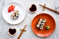 Sushi roll with salmon and avocado on plate with soy sauce, chopstick, wasabi on grey stone background top view Royalty Free Stock Photo