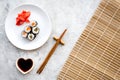 Sushi roll with salmon and avocado on plate with soy sauce, chopstick, wasabi on mat on grey stone background top view Royalty Free Stock Photo