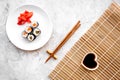 Sushi roll with salmon and avocado on plate with soy sauce, chopstick, wasabi on mat on grey stone background top view Royalty Free Stock Photo