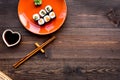 Sushi roll with salmon and avocado on plate with soy sauce, chopstick, wasabi on wooden table background top view Royalty Free Stock Photo