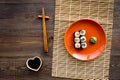 Sushi roll with salmon and avocado on plate with soy sauce, chopstick, wasabi on wooden table background top view Royalty Free Stock Photo