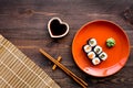 Sushi roll with salmon and avocado on plate with soy sauce, chopstick, wasabi on wooden table background top view Royalty Free Stock Photo