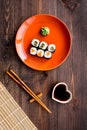 Sushi roll with salmon and avocado on plate with soy sauce, chopstick, wasabi on wooden table background top view Royalty Free Stock Photo