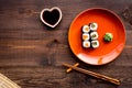 Sushi roll with salmon and avocado on plate with soy sauce, chopstick, wasabi on wooden table background top view Royalty Free Stock Photo