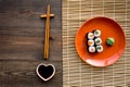 Sushi roll with salmon and avocado on plate with soy sauce, chopstick, wasabi on wooden table background top view Royalty Free Stock Photo