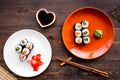 Sushi roll with salmon and avocado on plate with soy sauce, chopstick, wasabi on wooden table background top view Royalty Free Stock Photo