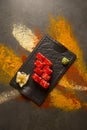 Sushi roll with salmon, red flying fish roe Tobiko with wasabi, ginger on black plate, Scattered spices on background Royalty Free Stock Photo