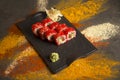 Sushi roll with salmon, red flying fish roe Tobiko with wasabi, ginger on black plate, Scattered spices on background Royalty Free Stock Photo