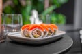 Sushi roll with salmon, shrimp, avocado and cream cheese on a plate close-up