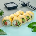 Sushi roll with salmon wrapped in egg omelet. With cucumber crab and cream cheese. Decorated with greenery. In the background is a Royalty Free Stock Photo