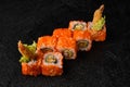 Sushi roll with shrimp inside and red flying fish roe on top on black background Royalty Free Stock Photo