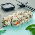 Sushi roll sprinkled with sesame seeds. With salmon, shrimp, cream cheese and vegetables. Decorated with greenery. In the Royalty Free Stock Photo