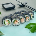 Sushi roll with teriyaki salmon, cream cheese and vegetables. Sprinkled with black masago caviar. Decorated with greenery. In the Royalty Free Stock Photo