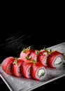 Sushi roll with tuna, cream cheese, cucumber, rice in plate on black wooden table Royalty Free Stock Photo