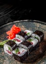 Sushi roll with tuna, cucumber, cream cheese, rice in plate on black wooden table Royalty Free Stock Photo